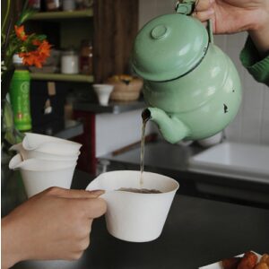 A Kettle Filling a Petite Cup with Tea