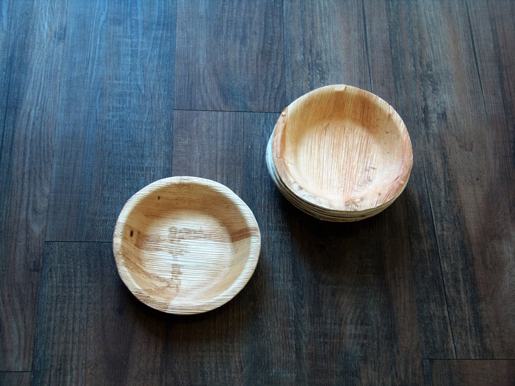 Round Palm Leaf Plates on a dark brown wooden table.